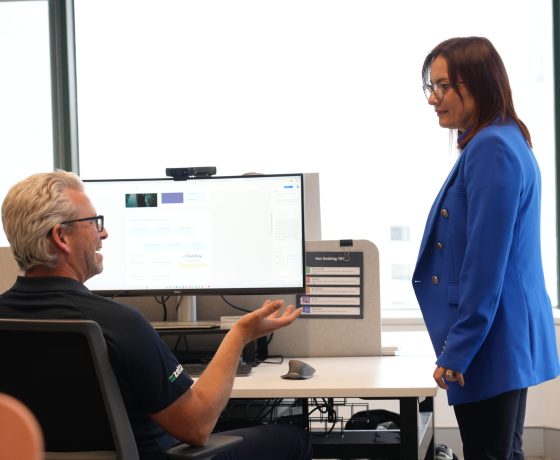 Zetta team member at his desk talking a colleague through what is on his screen, Perth office