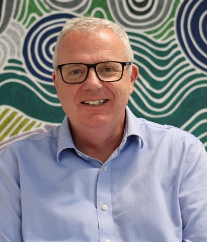 Andrew Speirs, Zetta CEO, smiling in front of Aboriginal artwork in the Perth office