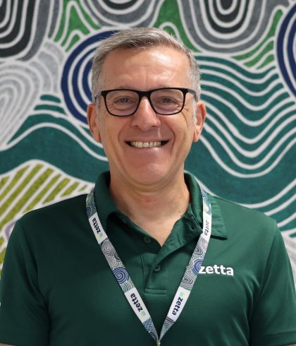 Carlo Calleri of Zetta smiling in front of Aboriginal artwork in the Perth office