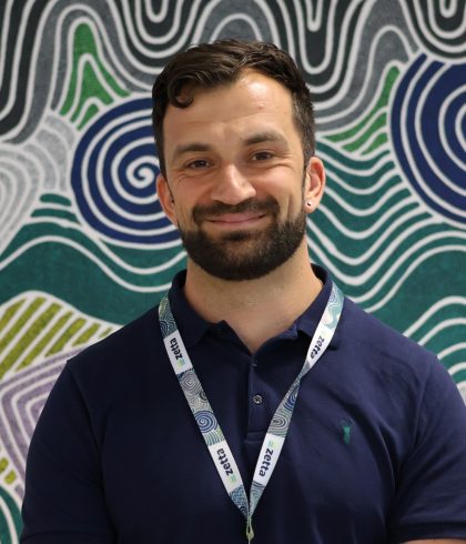 Jake Batty, Zetta Professional Services Manager, smiling in front of Aboriginal artwork in the Perth office