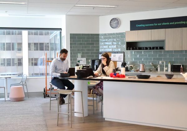 Two Zetta team members working at the kitchen island under the purpose sign: Creating success for our clients and providing growth opportunities for our teams