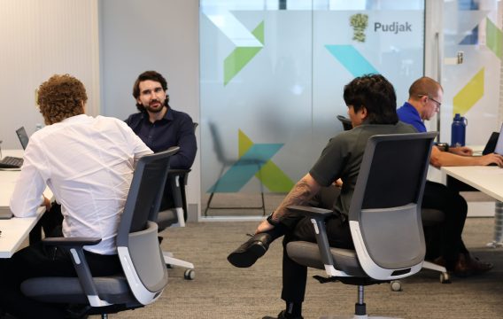 Zetta team members talking across their desks in the open-plan Perth office