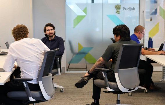 Zetta team members talking across their desks in the open-plan Perth office